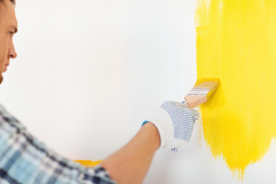 man painting the wall yellow